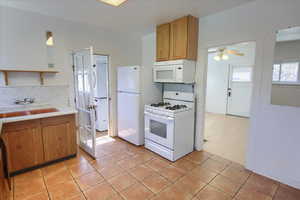 Kitchen with white appliances, a ceiling fan, light countertops, a sink, and light tile patterned flooring