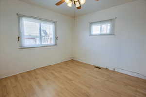 Spare room with light wood-style floors, a healthy amount of sunlight, and a ceiling fan