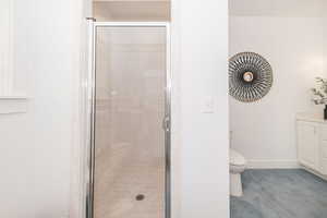 Bathroom with a stall shower, vanity, toilet, and baseboards