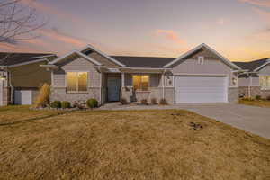 View of front facade with board and batten siding, concrete driveway, a front yard, a garage, and brick siding