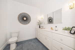 Bathroom with toilet, vanity, and baseboards