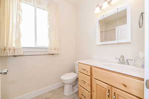 Bathroom with baseboards, vanity, and toilet