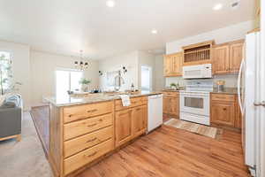 Kitchen featuring visible vents, light wood-type flooring, light brown cabinets, a sink, and white appliances