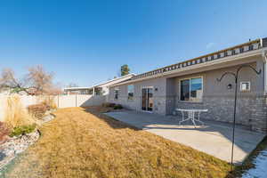 Back of property featuring brick siding, a lawn, stucco siding, a fenced backyard, and a patio