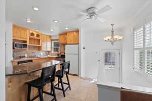 Kitchen with ornamental molding, appliances with stainless steel finishes, a sink, backsplash, and light tile patterned flooring