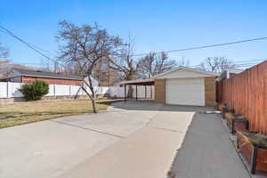 Exterior space featuring a fenced backyard, a garage, brick siding, concrete driveway, and a lawn