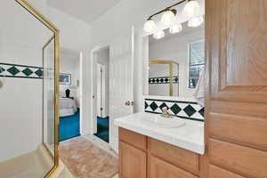 Bathroom featuring tasteful backsplash, a shower stall, vanity, and ensuite bathroom