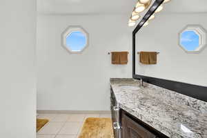 Bathroom with vanity, baseboards, and tile patterned floors