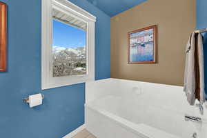 Bathroom featuring a garden tub, baseboards, a mountain view, and tile patterned floors