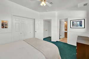 Bedroom featuring visible vents, ceiling fan, ensuite bathroom, dark carpet, and a closet