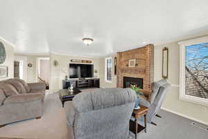 Carpeted living room with a fireplace, visible vents, a textured ceiling, and ornamental molding