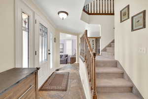 Foyer entrance with crown molding and stairway