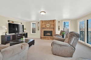 Carpeted living room featuring a textured ceiling, plenty of natural light, a fireplace, and crown molding