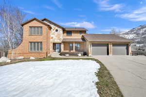 View of front facade with a garage, driveway, stone siding, a mountain view, and brick siding