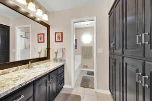 Bathroom with baseboards, visible vents, tile patterned floors, vanity, and a bath