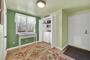 Laundry area with visible vents, washer / dryer, light wood-type flooring, laundry area, and baseboards