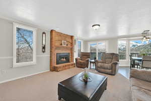 Living room with a textured ceiling, visible vents, baseboards, a brick fireplace, and carpet