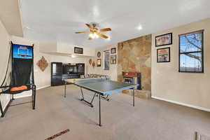 Rec room featuring carpet floors, a fireplace, baseboards, and a ceiling fan