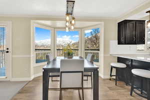 Dining space featuring a healthy amount of sunlight, light wood-style flooring, and ornamental molding