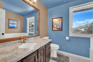 Half bathroom with toilet, tile patterned flooring, vanity, and baseboards