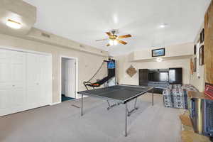 Playroom with ceiling fan, carpet, visible vents, and baseboards