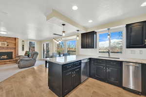 Kitchen with a sink, a peninsula, open floor plan, and stainless steel dishwasher