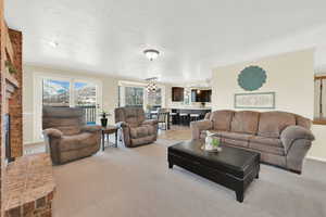 Living area featuring a textured ceiling, crown molding, a chandelier, and light colored carpet