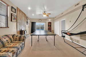 Game room with ceiling fan, visible vents, a wealth of natural light, and light colored carpet