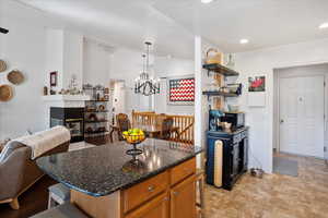 Kitchen with a fireplace, hanging light fixtures, brown cabinetry, open floor plan, and a kitchen breakfast bar