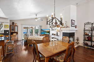 Dining area with vaulted ceiling, a textured ceiling, a tile fireplace, and dark wood-style floors