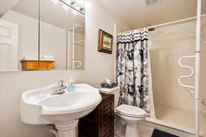 Bathroom with visible vents, a sink, a shower stall, and toilet