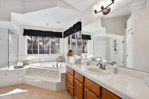 Bathroom with a stall shower, a garden tub, vanity, and an inviting chandelier