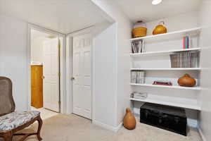 Living area featuring light colored carpet and baseboards