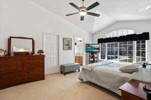 Bedroom featuring light carpet, connected bathroom, a ceiling fan, and lofted ceiling