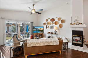 Living area with lofted ceiling, a fireplace, a ceiling fan, and wood finished floors