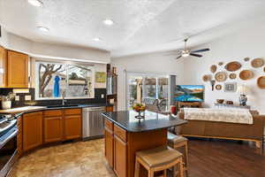 Kitchen featuring a kitchen island, a sink, open floor plan, appliances with stainless steel finishes, and backsplash