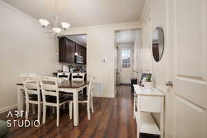 Dining area with dark wood-style flooring, a notable chandelier