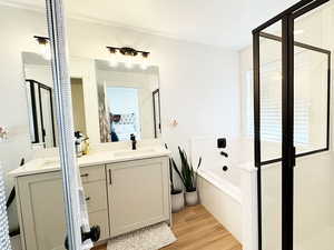 Full bath featuring wood finished floors, vanity, a bath, and ensuite bathroom