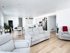 Living room with a textured ceiling, baseboards, visible vents, and light wood-style floors