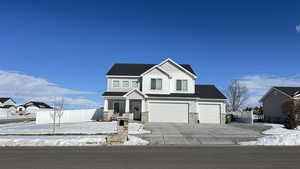 View of front of property with board and batten siding, fence, a garage, stone siding, and driveway