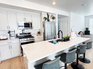 Kitchen with a breakfast bar, light wood finished floors, stainless steel appliances, and a sink