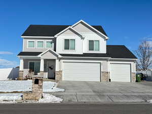 View of front of property featuring stone siding, board and batten siding, fence, and driveway