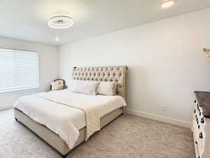 Bedroom featuring light carpet and baseboards