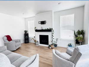 Living area with a fireplace, baseboards, and wood finished floors