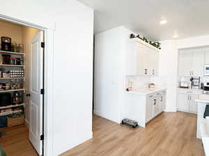 Kitchen featuring light countertops, light wood finished floors, and white cabinets