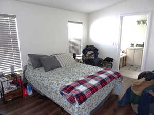 Bedroom featuring ensuite bath and dark wood-type flooring