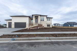 Prairie-style house with driveway, stone siding, an attached garage, and a residential view