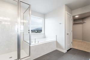 Bathroom featuring a garden tub, a shower stall, baseboards, and tile patterned floors