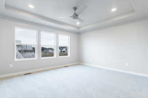 Empty room with recessed lighting, a raised ceiling, visible vents, and baseboards