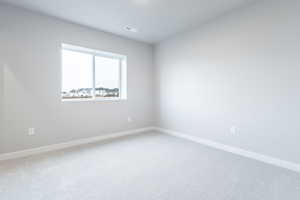 Carpeted empty room with baseboards and visible vents